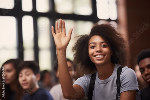 Young woman raising hand in a classroom setting, smiling, with diverse students in the background. photo