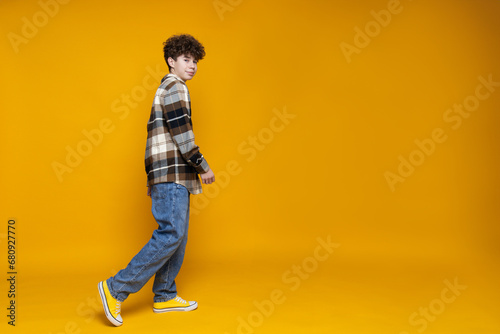 Attractive, curly boy teenager on a yellow background.