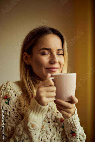 A smiling girl, holding a cup of coffee, spending the autumn day indoors.