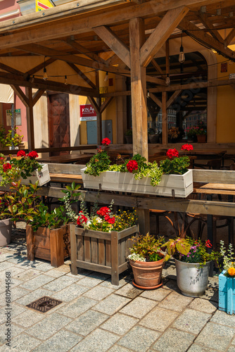 Town flowers in the big wooden pots on street. Interior street cafe with flowers in wooden pot. High quality photo