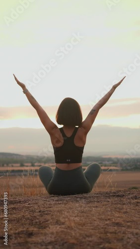 Back view of serene young woman enjoying meditation at the evening nature
