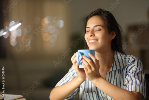 Happy woman drinking tea in the night at home