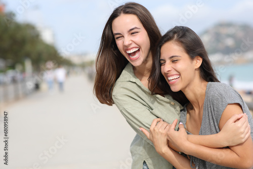 Two happy friends hugging and laughing outdoors