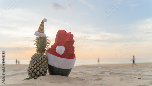 Santa Claus pineapple and watermelon couple wearing stylish sunglasses on the sand contrasting with the sea. wearing a christmas hat Christmas and New Year holiday ideas on the beach, 
