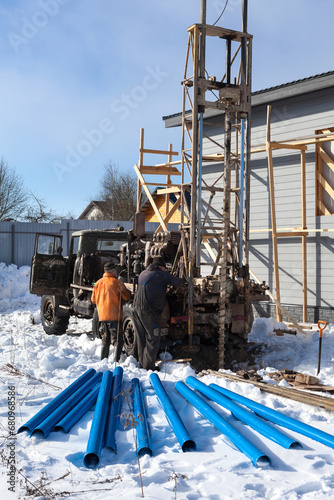 Drilling for water with truck and metall drill, blue pipes for inside installing