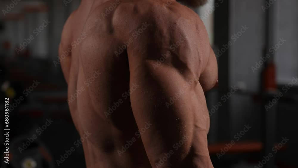 Topless man doing an exercise with a barbell in the gym. Bicep curls with weights.