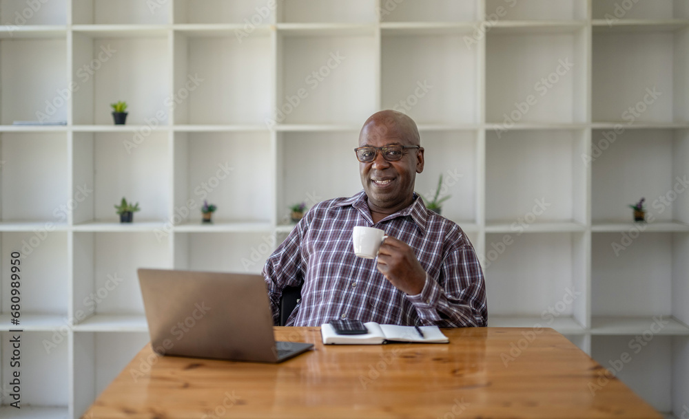 Senior black man taking a coffee break while working on a laptop. Senior black man taking a coffee break while working on a laptop.