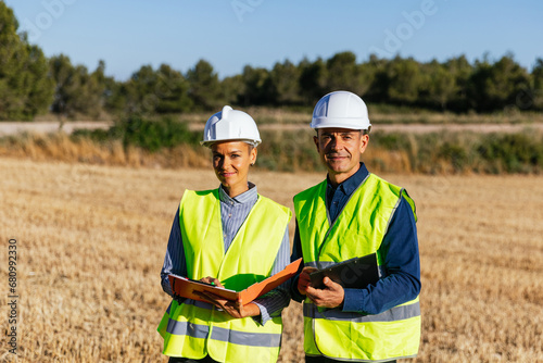 Engineers in work clothes stand on a sunny day in a rural field.