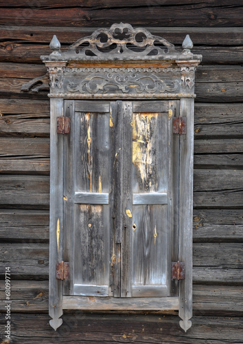 Window with closed shutters and decorative wooden elements on the wall of a wooden house. Quality image for your project