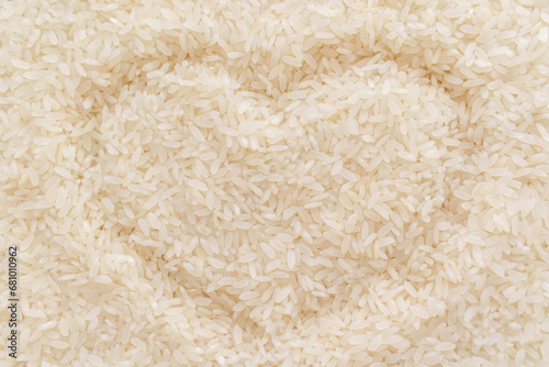 Uncooked rice with heart shape background. Parboiled rice texture backdrop. Cooking preparation in the kitchen concept. photo