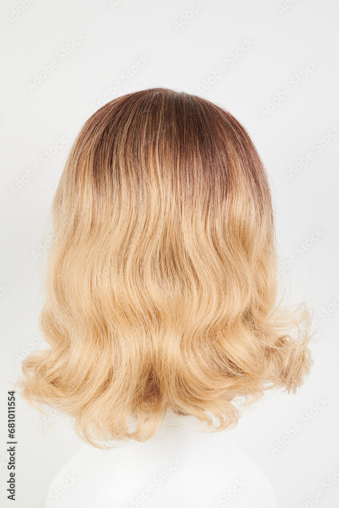 Naklejka premium Natural looking blonde fair wig on white mannequin head. Middle length hair cut on the plastic wig holder isolated on white background, back view