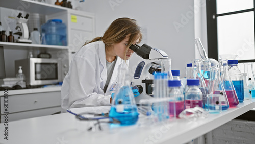 In the heart of science  young attractive blonde woman scientist intently working with microscope at laboratory  brewing discoveries through analysis