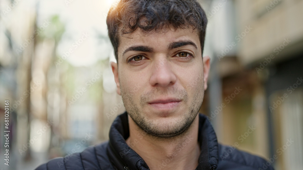 Young hispanic man standing with serious expression at street Young hispanic man standing with serious expression at street