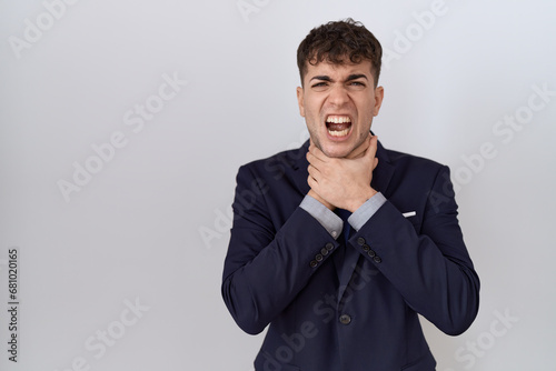 Young hispanic business man wearing suit and tie shouting and suffocate because painful strangle. health problem. asphyxiate and suicide concept.