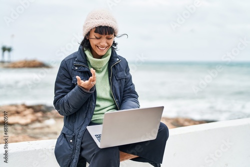 Young beautiful hispanic woman smiling confident having video call at seaside photo