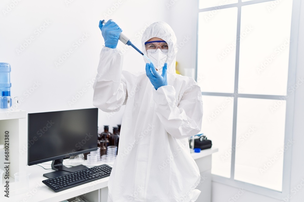 Young blonde woman scientist wearing security uniform pouring liquid on sample at laboratory Young blonde woman scientist wearing security uniform pouring liquid on sample at laboratory