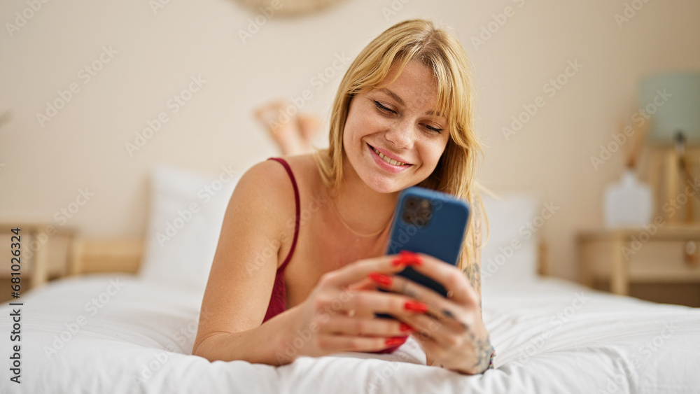 Young blonde woman wearing sensual lingerie lying on bed using smartphone at bedroom Young blonde woman wearing sensual lingerie lying on bed using smartphone at bedroom