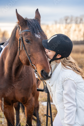 Beautiful blond professional female jockey kissing horse. Friendship with horse
