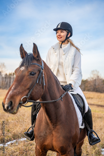 Pretty professional female jockey riding a horse in field in winter