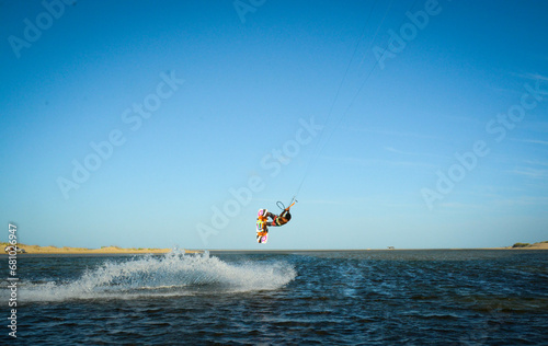 Kitsufista fazendo manobra no ar em lago no nordeste brasileiro com céu azul de fundo - Kitsurf
