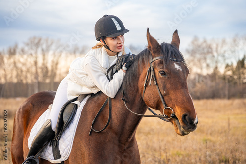 Beautiful blond professional female jockey riding a horse. Friendship with horse.