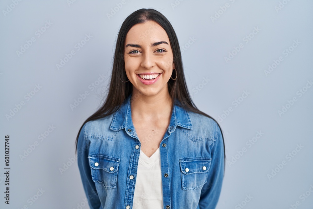Hispanic woman standing over blue background with a happy and cool smile on face. lucky person. - obrazy, fototapety, plakaty 