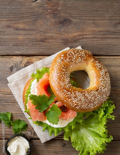 Bagels with salmon, cream cheese and lettuce on a wooden table; top view; copy space