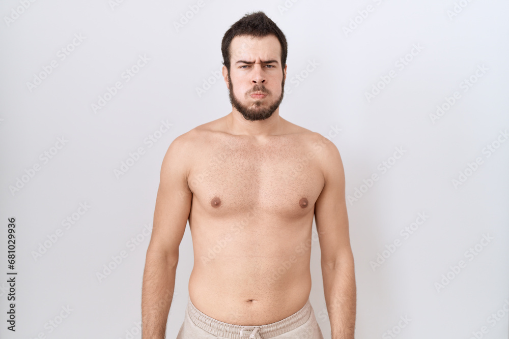 Young hispanic man standing shirtless over white background puffing cheeks with funny face. mouth inflated with air, crazy expression.