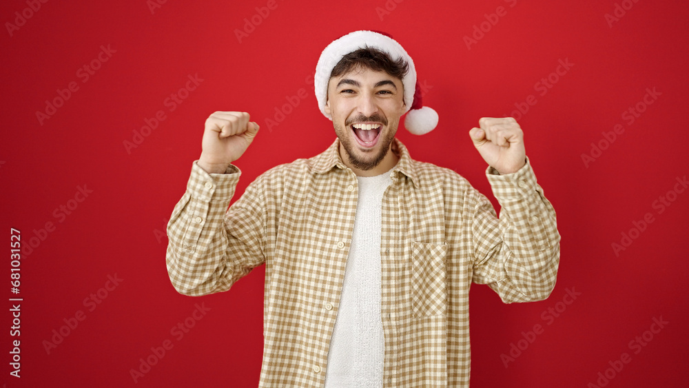 Young arab man wearing christmas hat with cheerful expression over isolated red background