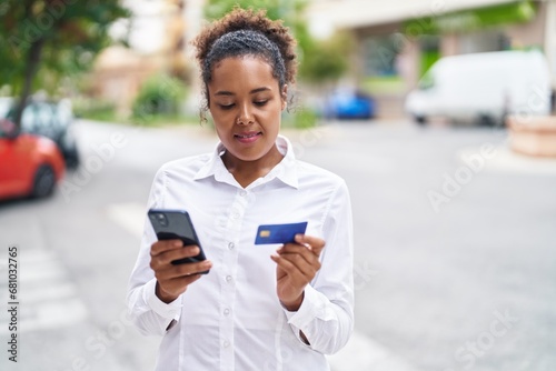 African american woman using smartphone and credit card at street