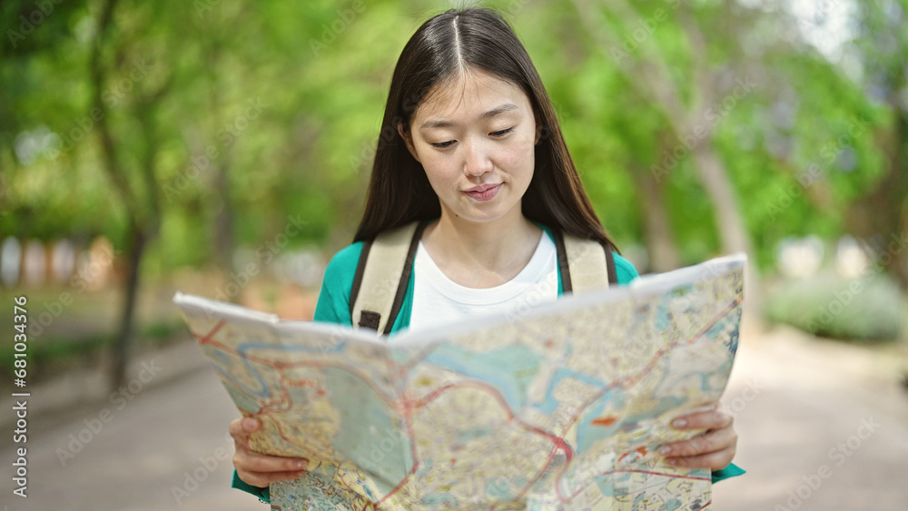 Young chinese woman tourist wearing backpack looking at city map at park Young chinese woman tourist wearing backpack looking at city map at park