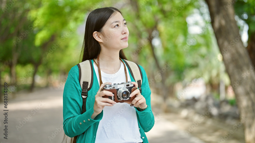 Young chinese woman tourist wearing backpack holding camera at park Young chinese woman tourist wearing backpack holding camera at park