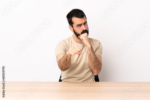 Caucasian man with beard in a table with fighting gesture.