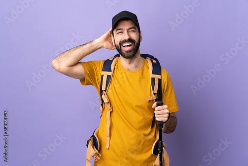 Caucasian handsome man with backpack and trekking poles over isolated background laughing