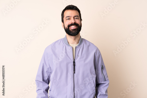 Caucasian man with beard wearing a jacket over isolated background laughing