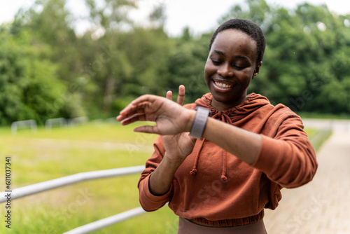 Black woman runner, smartwatch and rest for breathing, heart rate or health while training in summer. Woman, running and healthcare tech for exercise, workout and fitness at nature park.
