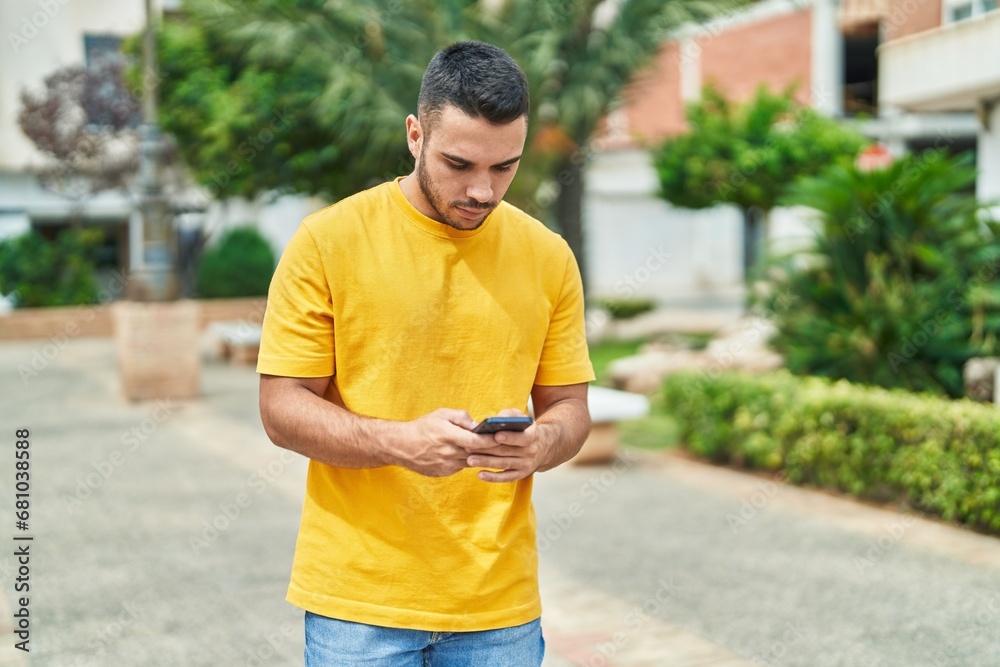 Young hispanic man using smartphone with serious expression at park Young hispanic man using smartphone with serious expression at park