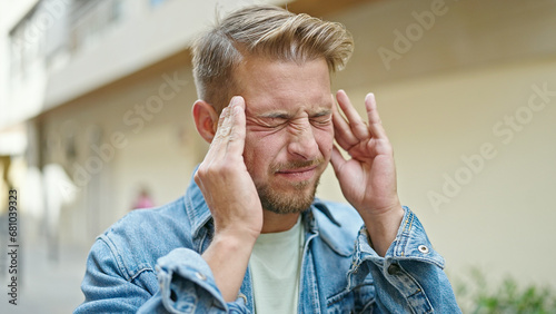 Young caucasian man suffering for headache at street