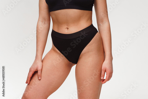 A woman with a beautiful feminine figure in black lingerie with overweight, cellulite and stretch marks.