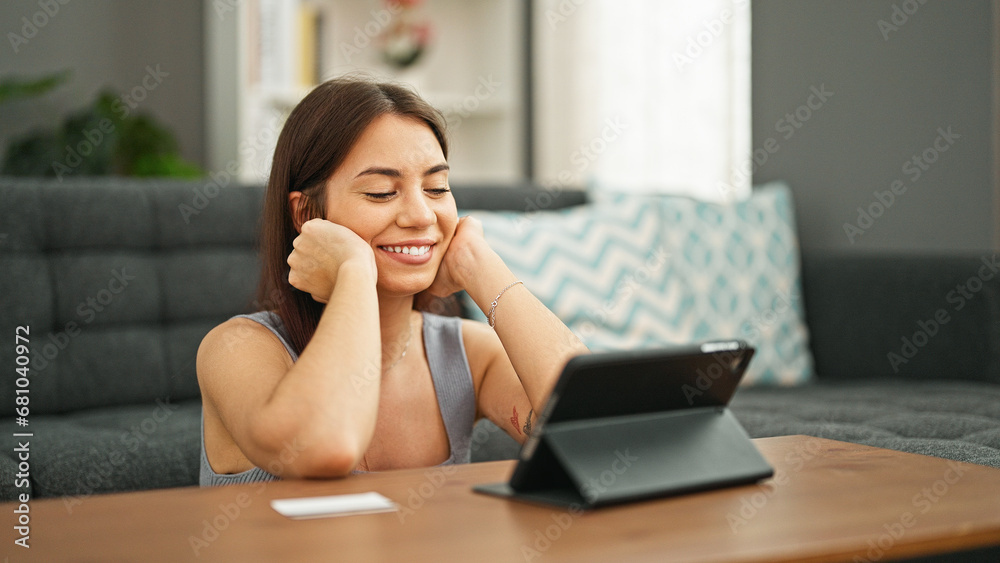 Young beautiful hispanic woman shopping with touchpad and credit card sitting on floor at home Young beautiful hispanic woman shopping with touchpad and credit card sitting on floor at home
