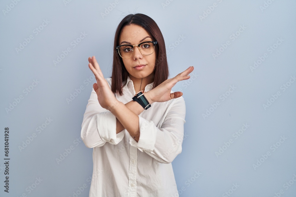 Young hispanic woman standing over white background rejection expression crossing arms doing negative sign, angry face