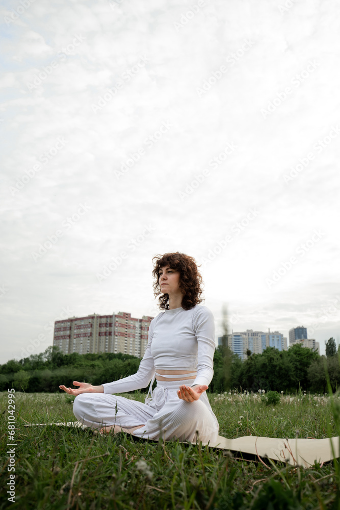 Concept of yoga training on fresh air. Young girl meditating in lotus pose. Female coach practicing retreat outdoor. Calm lady relaxing. Sports woman doing breathing exercises Concept of yoga training on fresh air. Young girl meditating in lotus pose. Female coach practicing retreat outdoor. Calm lady relaxing. Sports woman doing breathing exercises