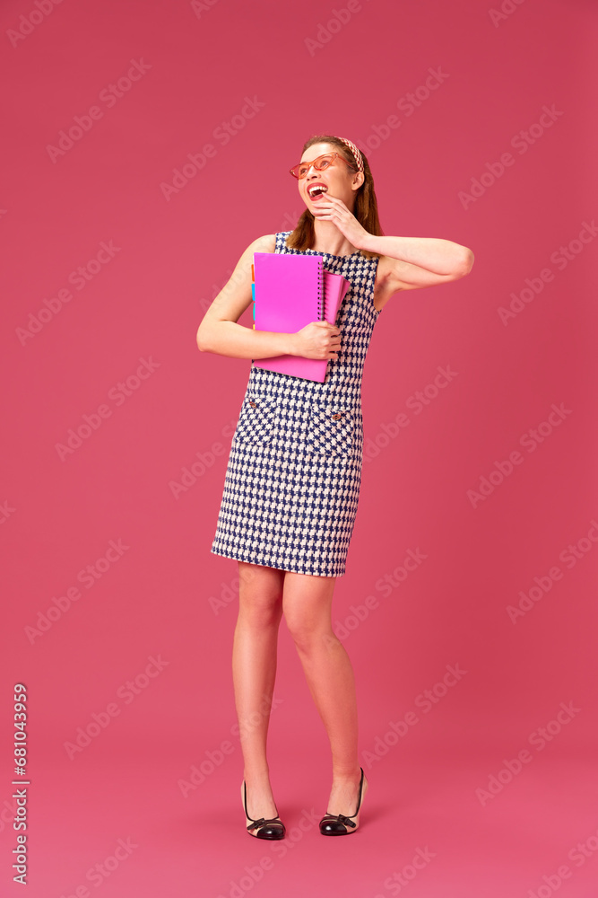 Happy, cheerful, smiling young girl with books and notebooks against against pink studio background. Excitement. Concept of youth, human emotions, education, lifestyle, fashion