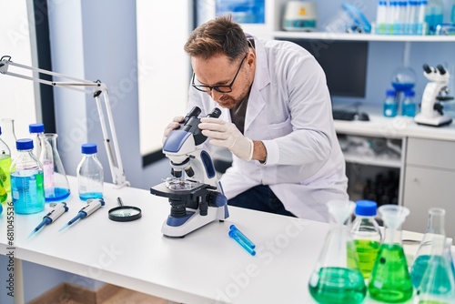 Young caucasian man scientist using microscope at laboratory