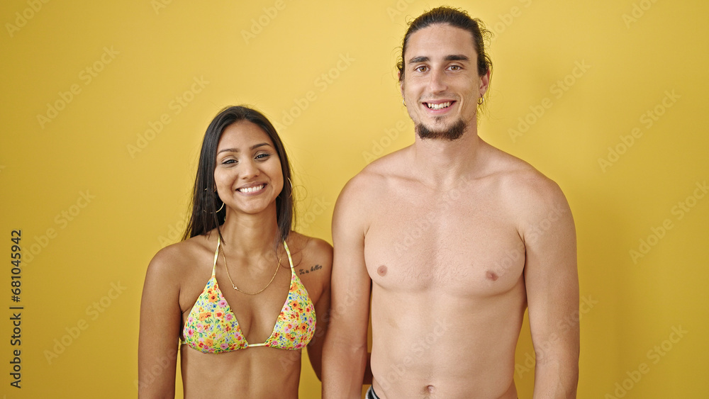 Man and woman tourist couple standing together smiling over isolated yellow background