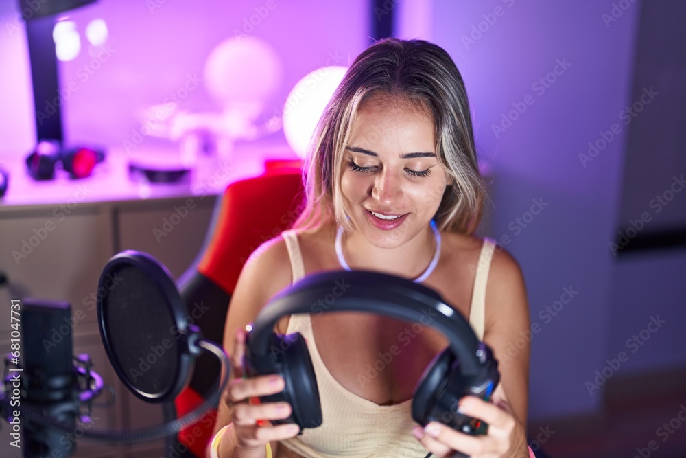 Young blonde woman streamer smiling confident holding headphones at gaming room Young blonde woman streamer smiling confident holding headphones at gaming room
