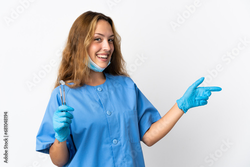Woman dentist holding tools isolated on white background pointing finger to the side and presenting a product