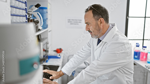 Concentrated middle-aged man with grey hair, immersed in groundbreaking science, harnesses computer power in the buzzing lab environment