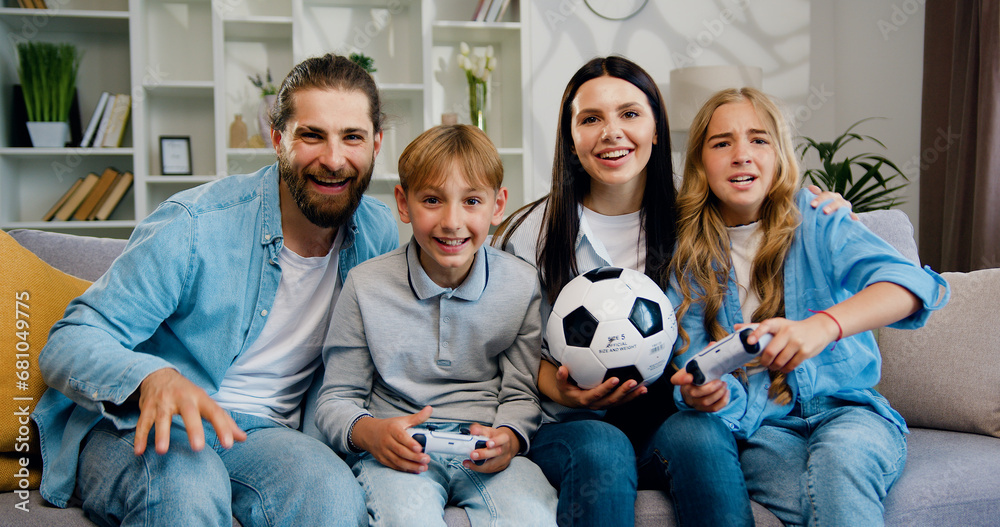 Two kids playing online on TV set at home enjoying video games and celebrating victory and parents which supporting them and rejoycing. Home family entertainment concept where cute emotional.