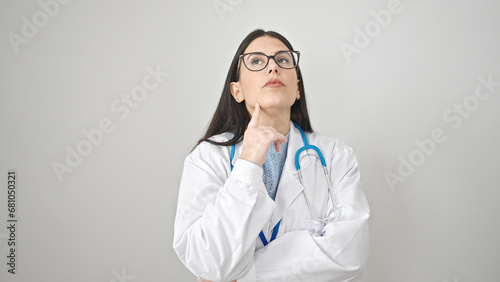 Young hispanic woman doctor standing with doubt expression thinking over isolated white background